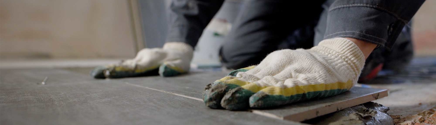 Close-up view of workers gloved hands installing flooring system