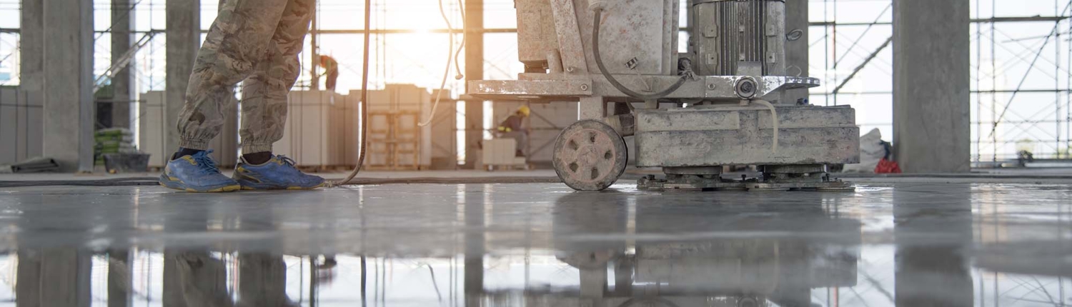 Worker in yellow vest using flooring equipment to smooth polished concrete