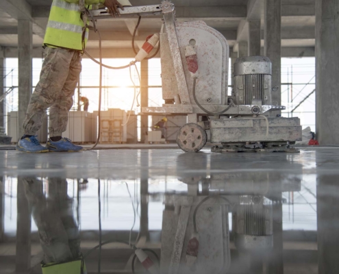 Worker in yellow vest using flooring equipment to smooth polished concrete
